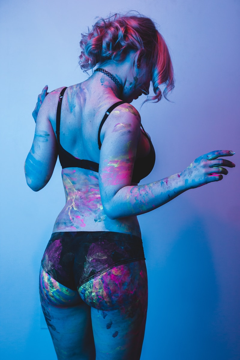 woman with paint on her body facing the wall