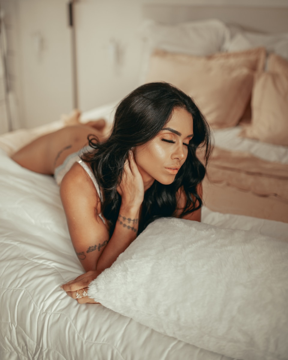 woman in white tank top lying on bed