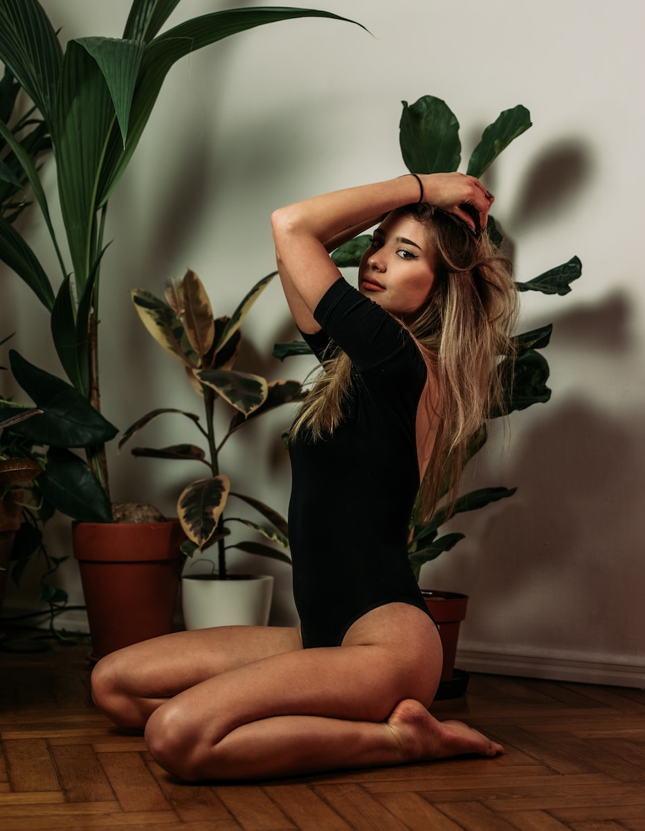 woman in black tank top sitting on brown wooden table