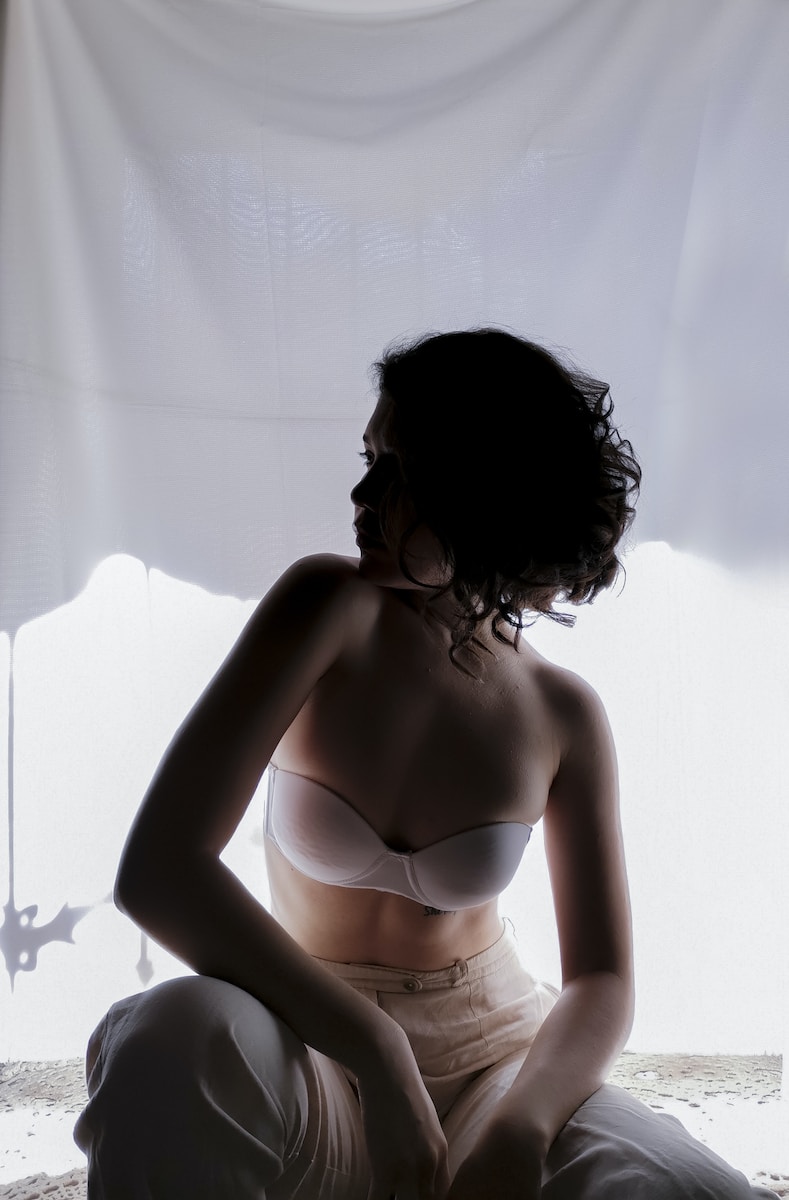 woman in white brassiere standing near white curtain