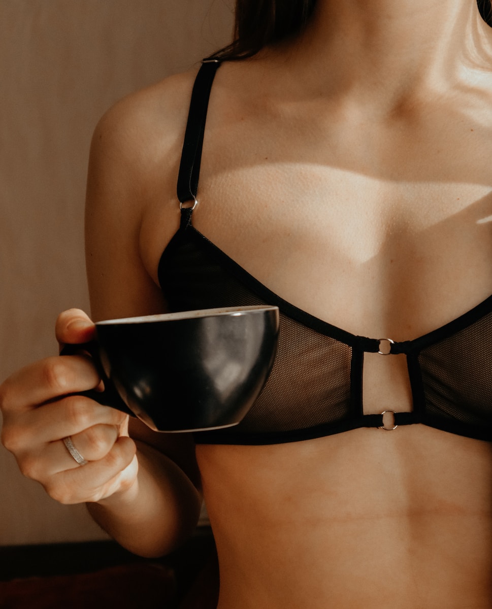 woman in black brassiere holding black ceramic bowl