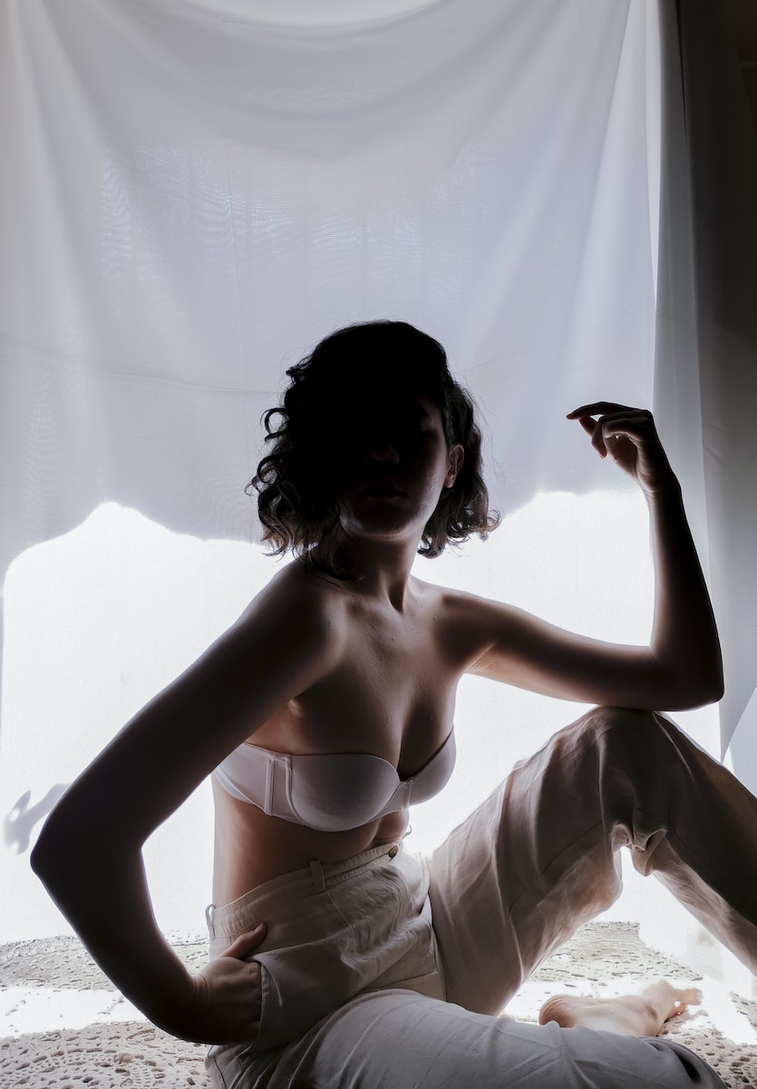 woman in white brassiere and white pants sitting on white textile