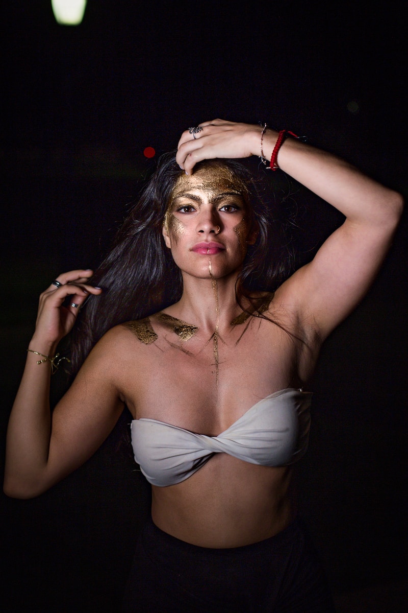 a woman in a white top with a gold face paint