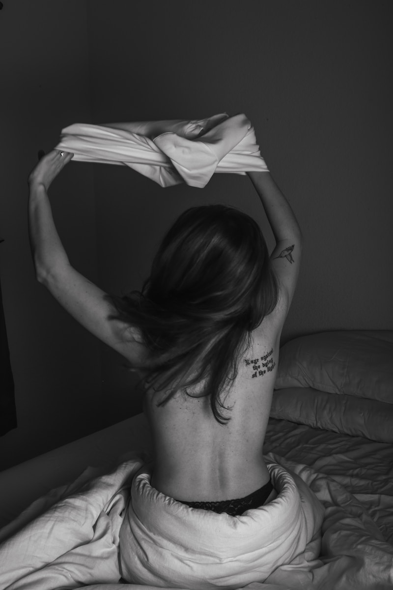 a woman sitting on top of a bed holding a towel